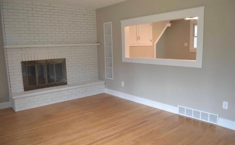 An empty living room with a fireplace and a window.