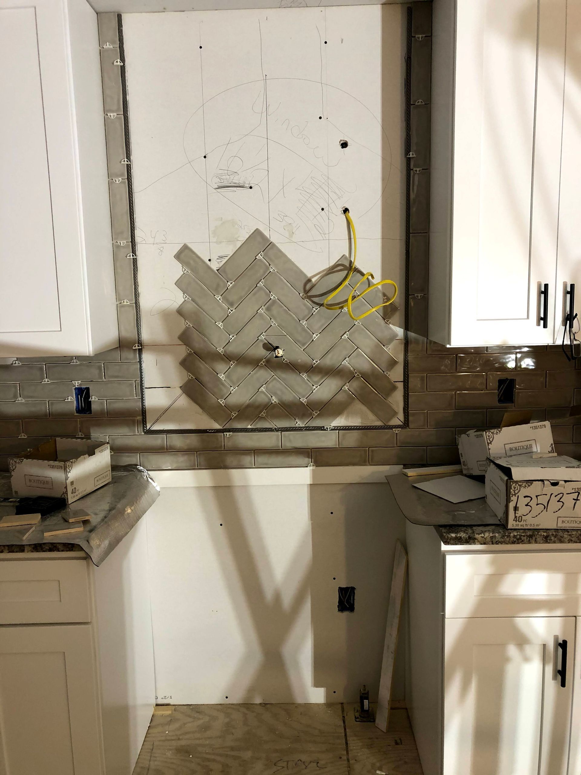 A kitchen with white cabinets and a brick wall.