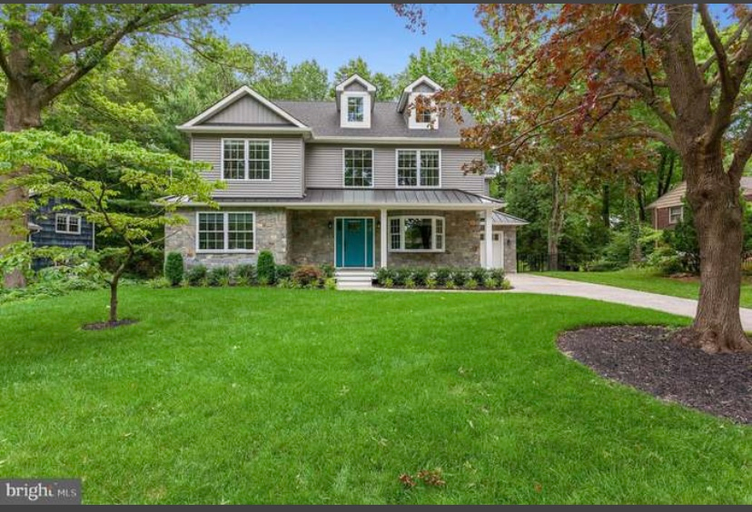 A large house with a lush green lawn and trees in front of it.