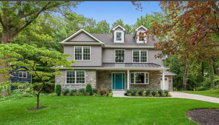 A large house with a lush green lawn and trees in front of it.