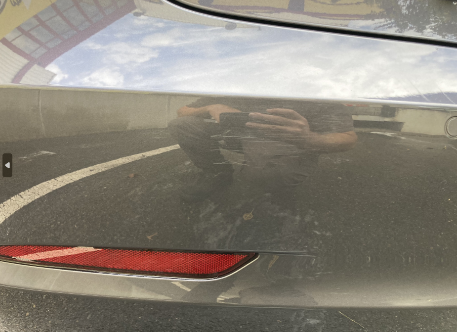 Une personne prend une photo de son reflet à l’arrière d’une voiture