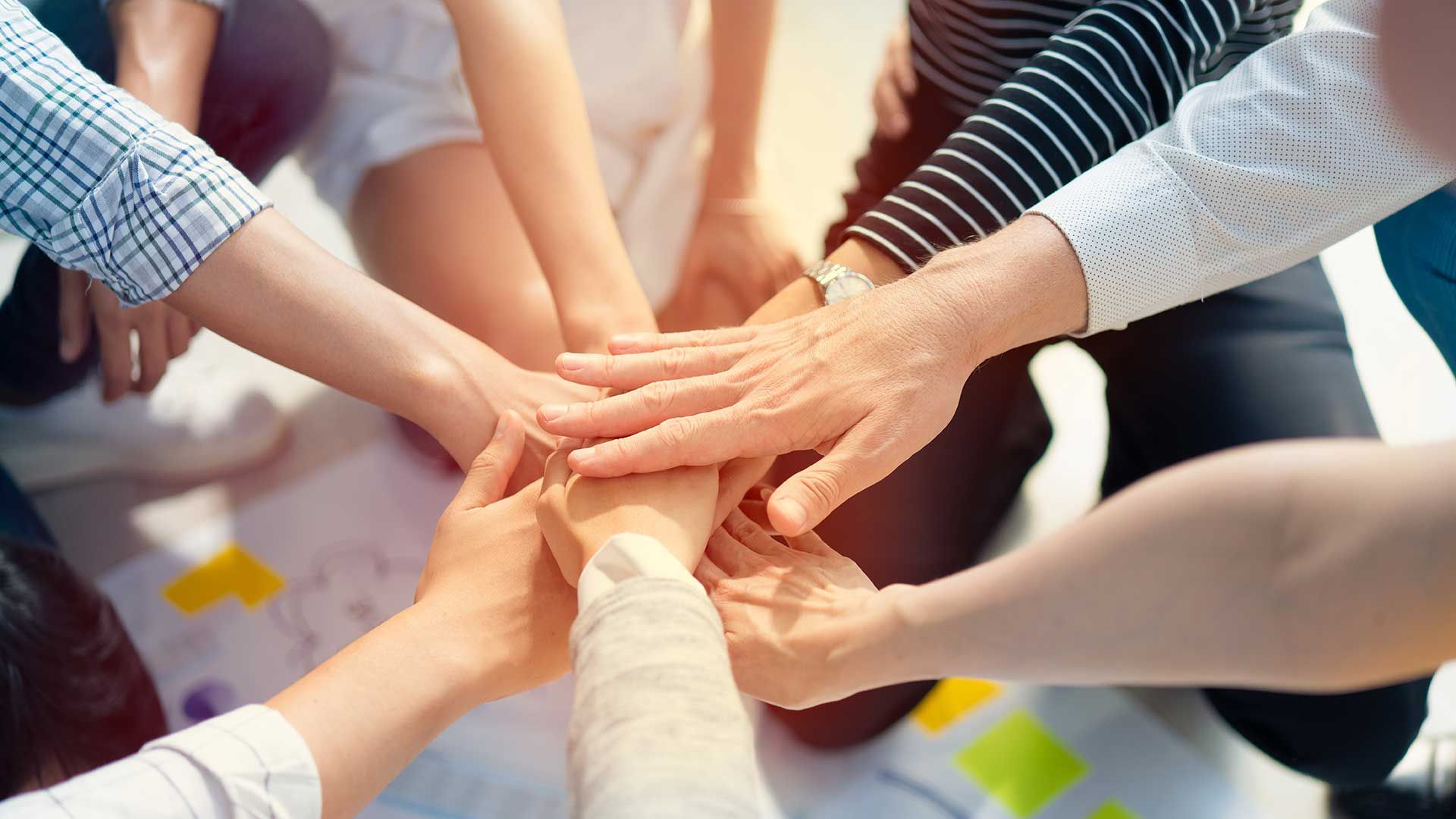 A group of people are putting their hands together in a circle.