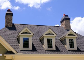 The roof of a house has a few chimneys on it