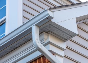 A close up of a gutter on the side of a house.