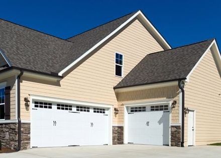 There are two garage doors on the side of a house.