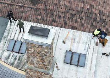 A group of people are working on the roof of a building.