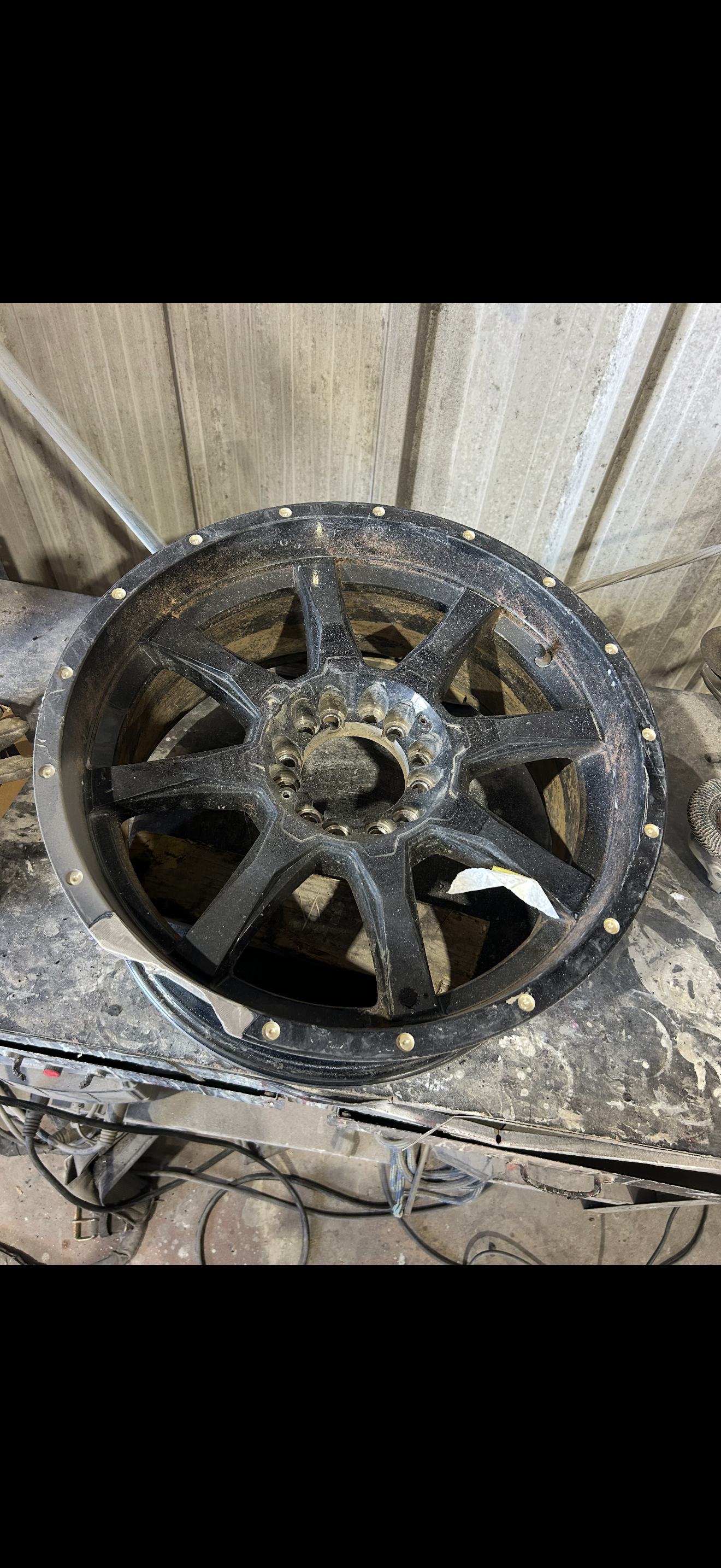 Black alloy wheel with debris, against a weathered wooden background.