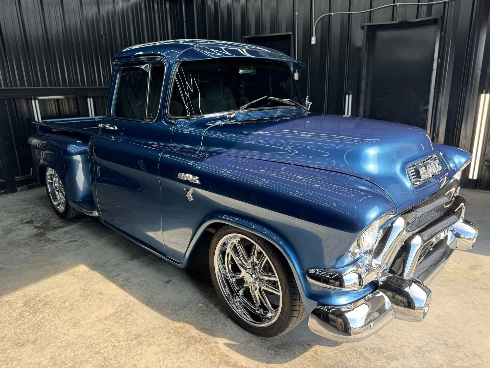 Blue classic GMC pickup truck with chrome wheels, parked, outdoors.
