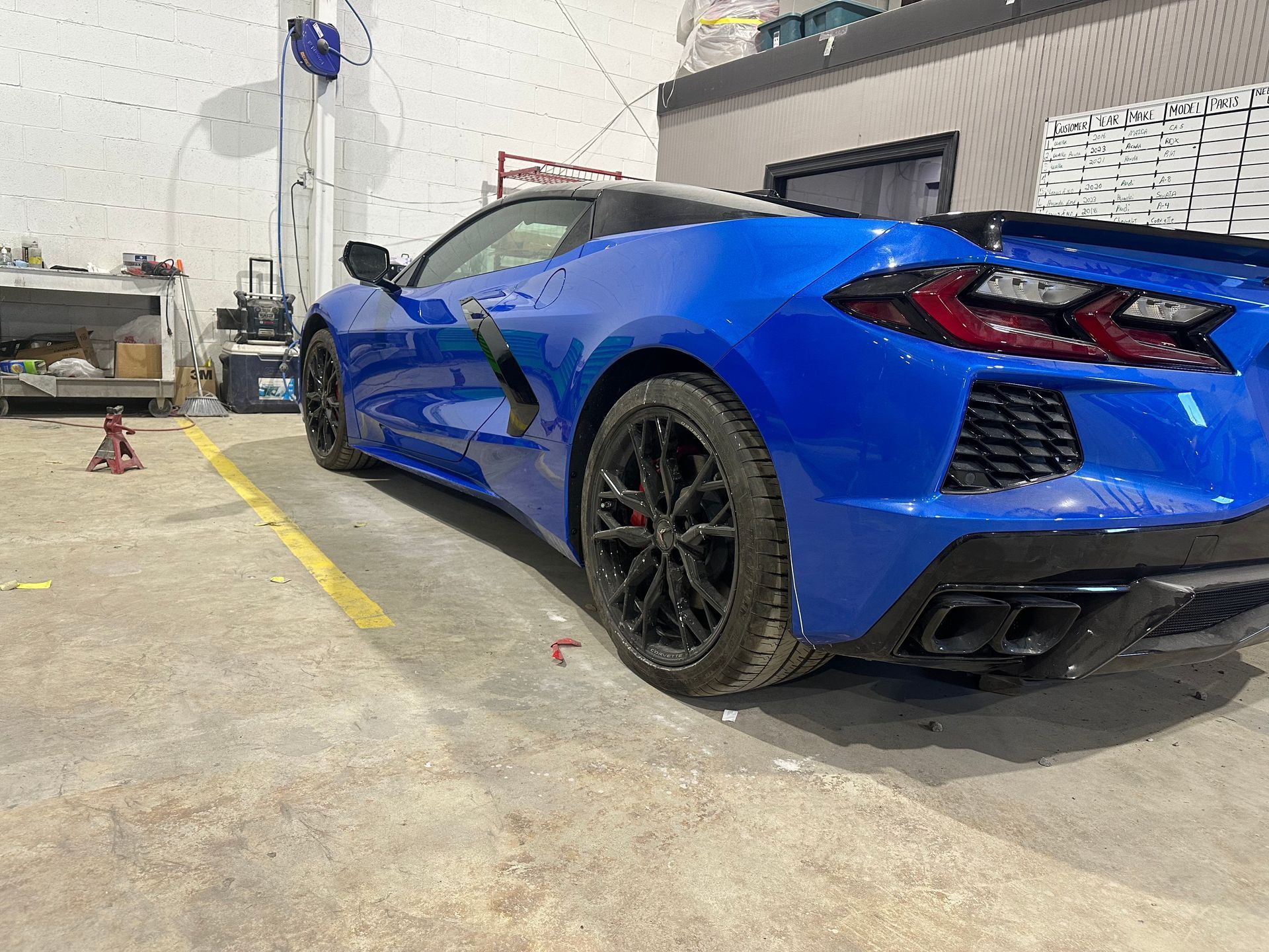 Blue Chevrolet Corvette sports car parked in a garage with black wheels.