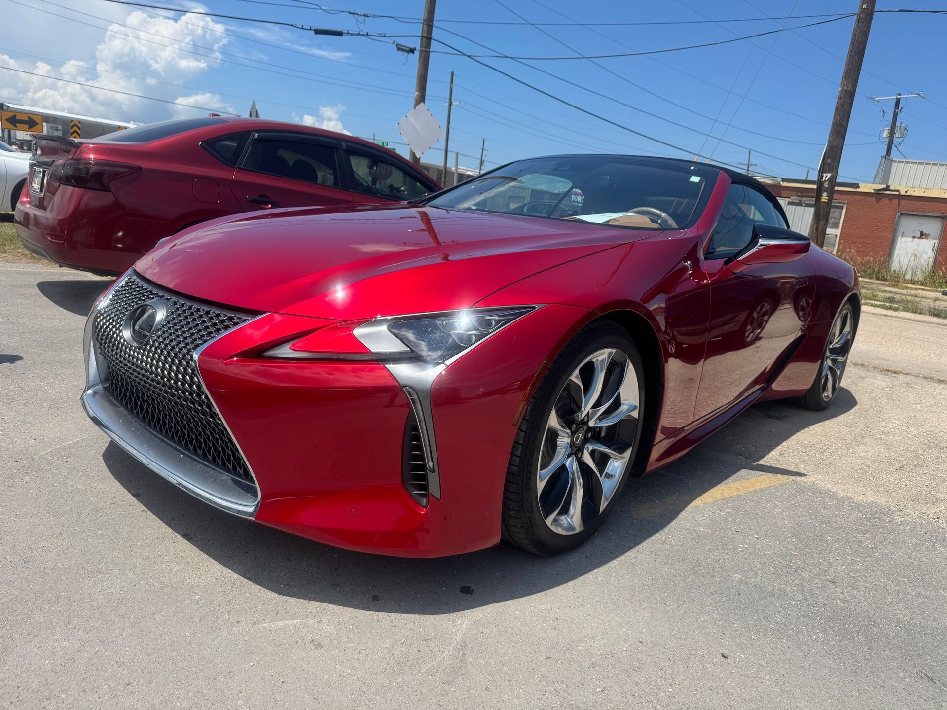Red Lexus LC convertible parked on asphalt on a sunny day.