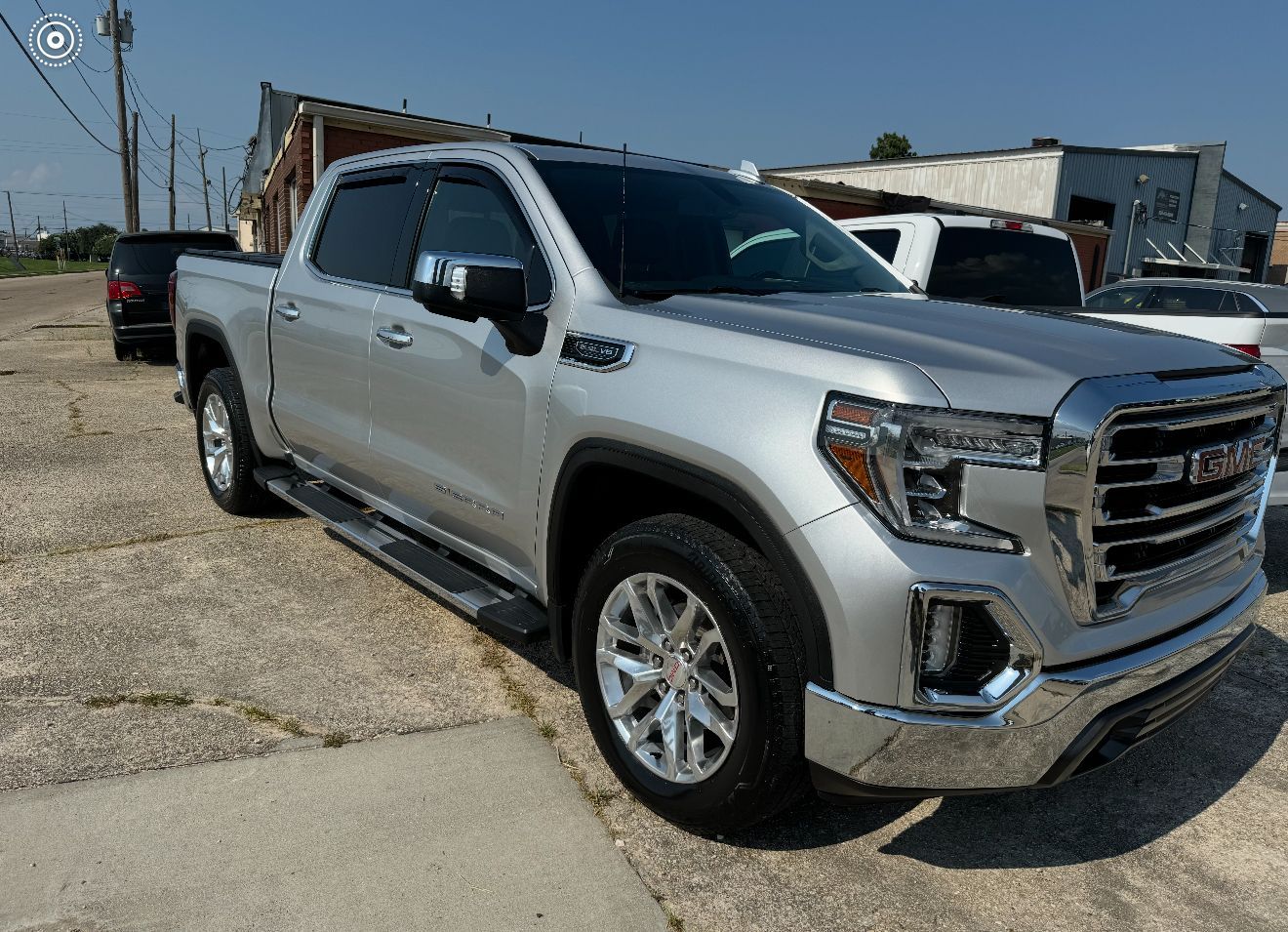 Silver GMC Sierra pickup truck parked on concrete, sunny day.