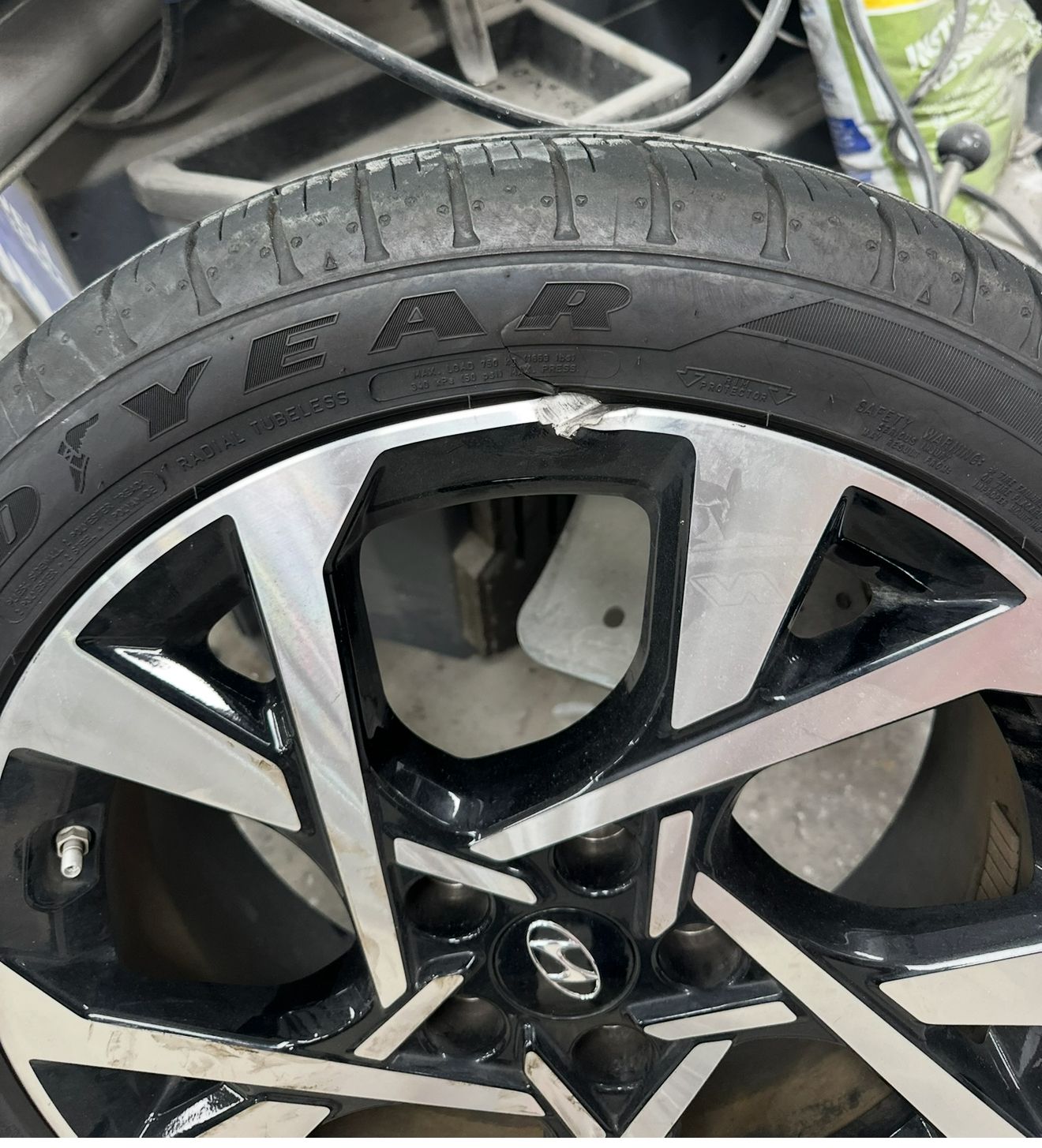 Close-up of a damaged black and silver car wheel with a Goodyear tire.
