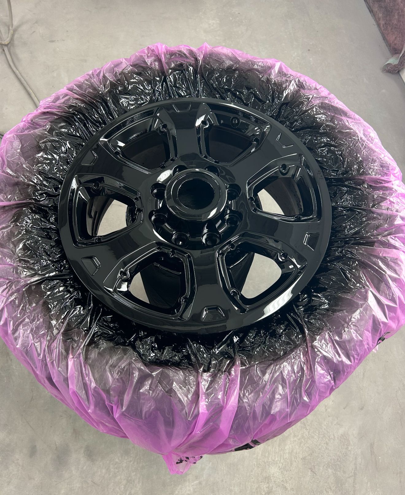 Black painted car wheel on a purple plastic surface.