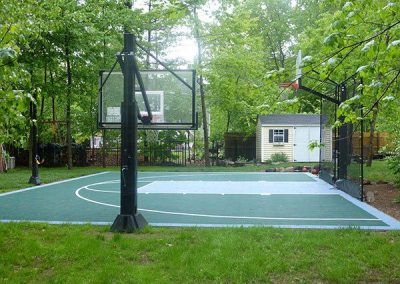 A basketball court in a backyard surrounded by trees.