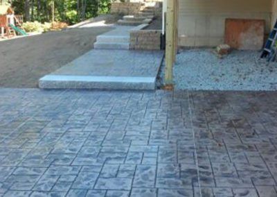 A concrete driveway with stairs leading up to a house.