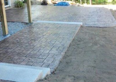 A concrete walkway is being built in a backyard.