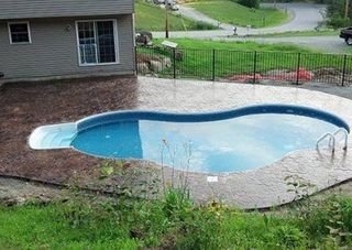 A large swimming pool is in the backyard of a house.