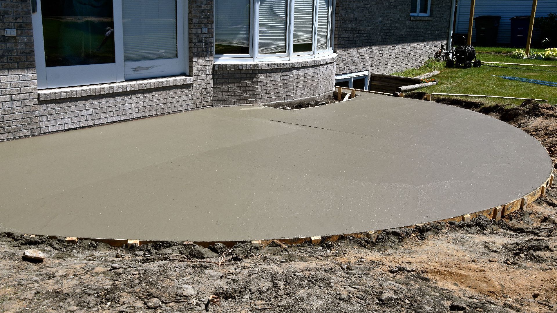 A concrete patio is being built in front of a house.