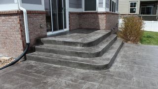 A concrete porch with stairs leading up to a house.