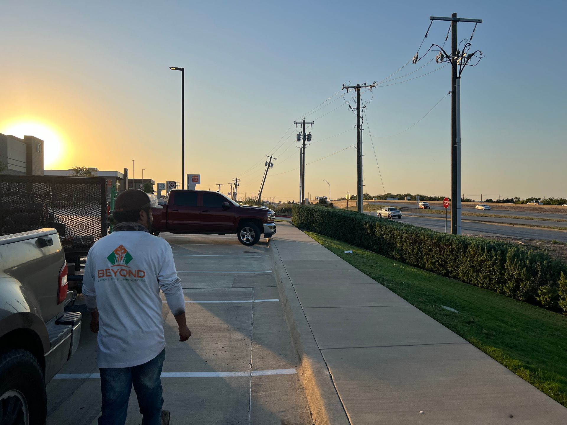 A man is walking down a sidewalk next to a parking lot.
