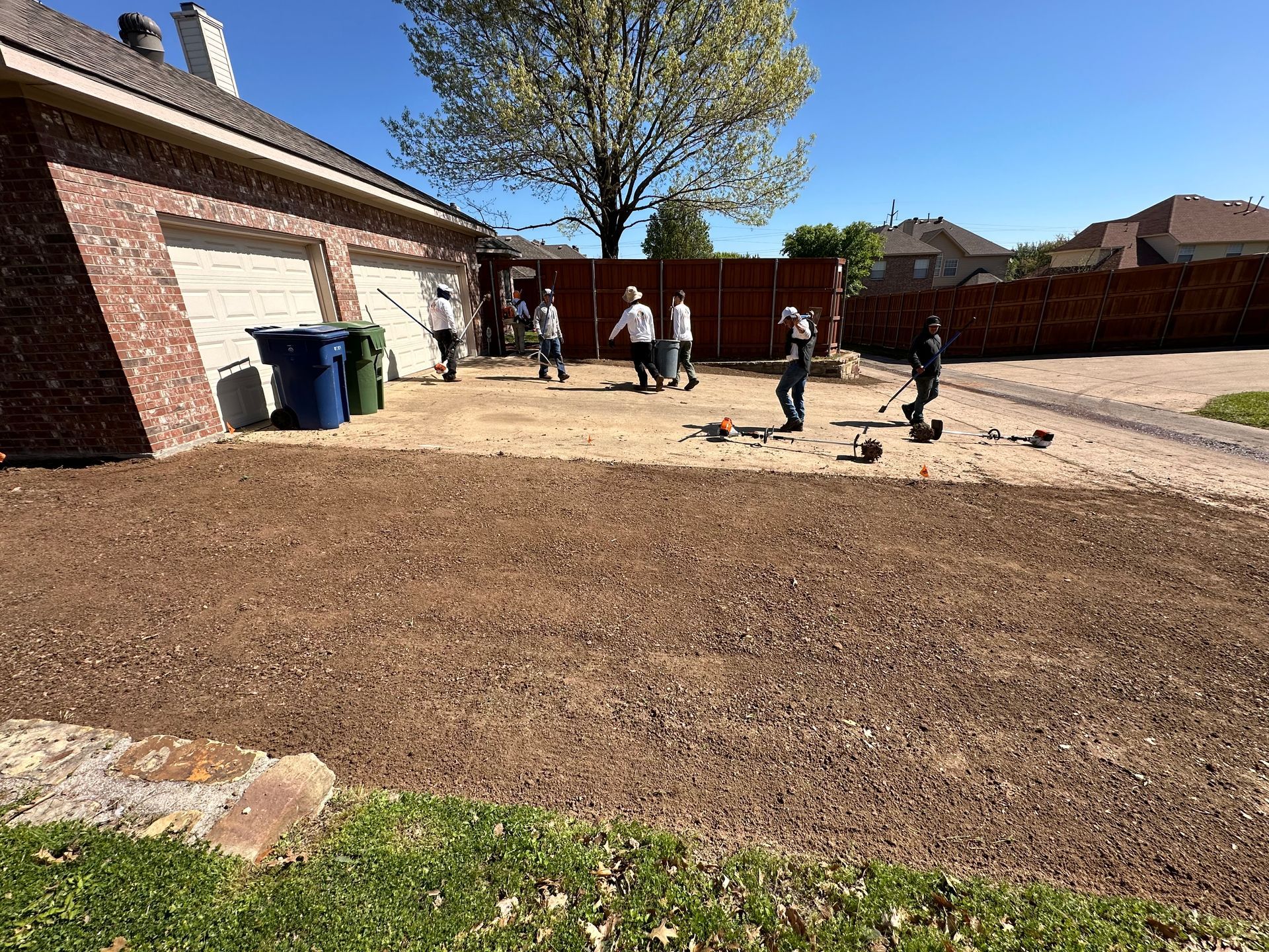 A group of people are working on a lawn in front of a house.