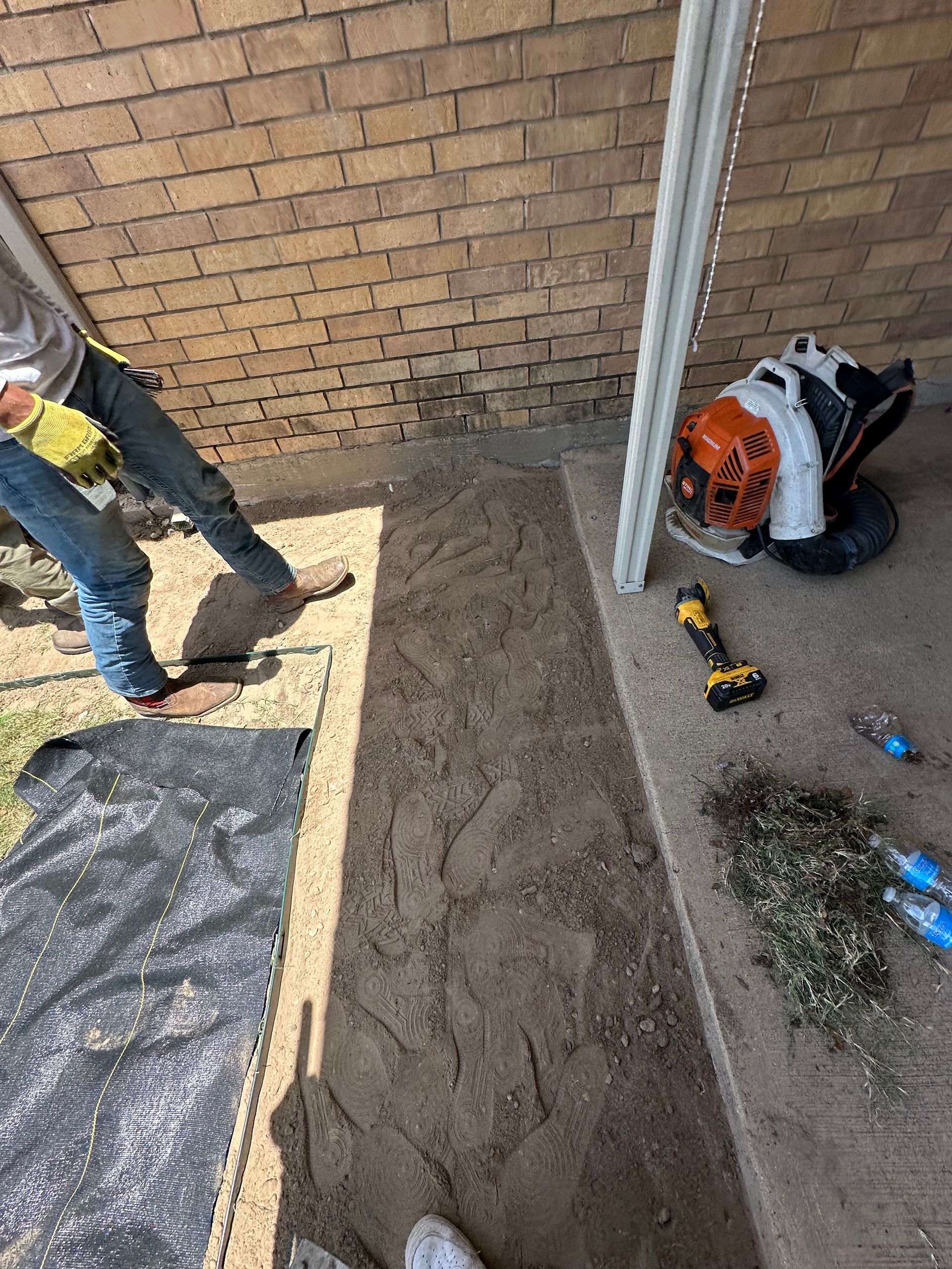 A man is standing on a porch next to a brick wall.