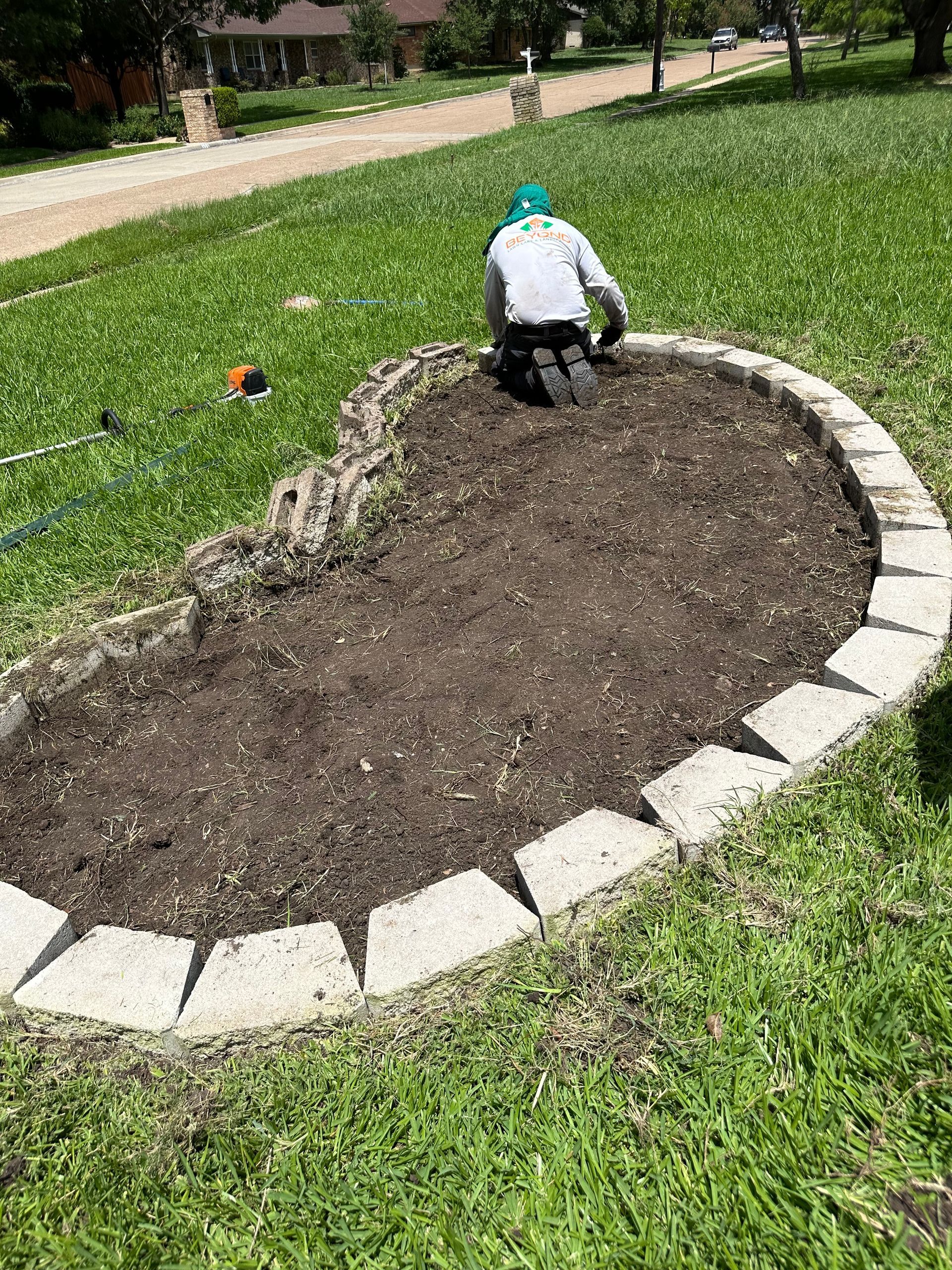 A man is kneeling in the dirt in a garden.