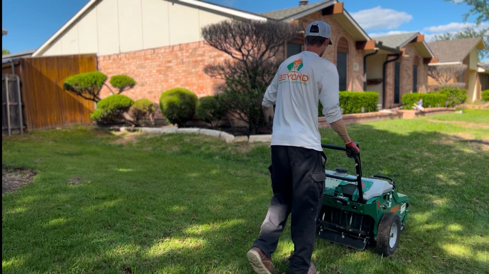 A man is walking across a lush green lawn with a lawn mower.
