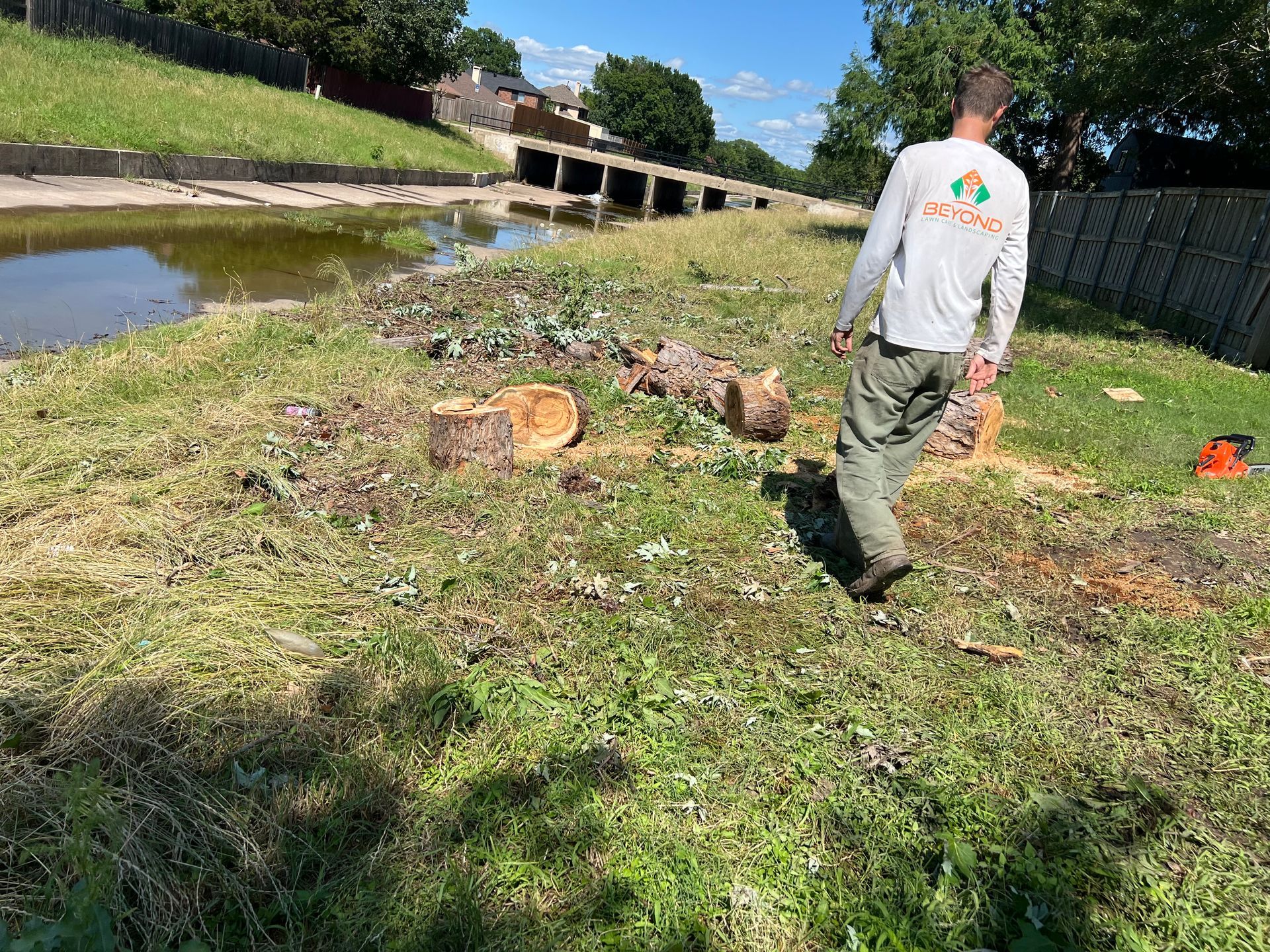 A man is walking through a grassy field next to a river.