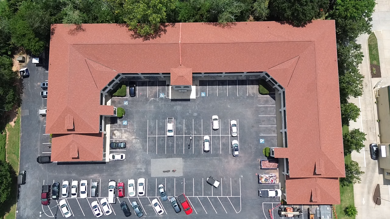 An aerial view of a building with a lot of cars parked in front of it