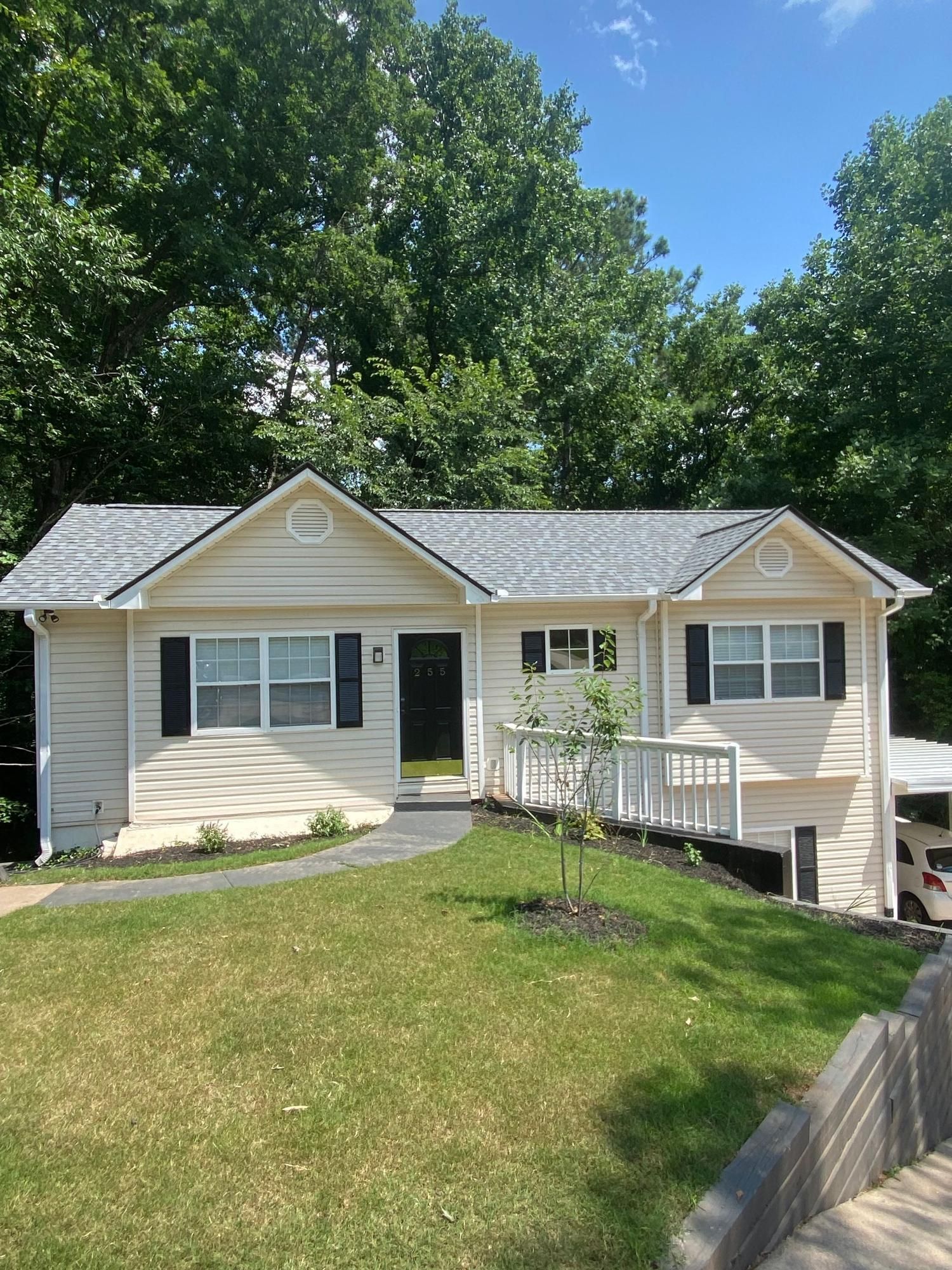 A white house with a gray roof is sitting on top of a lush green hill.