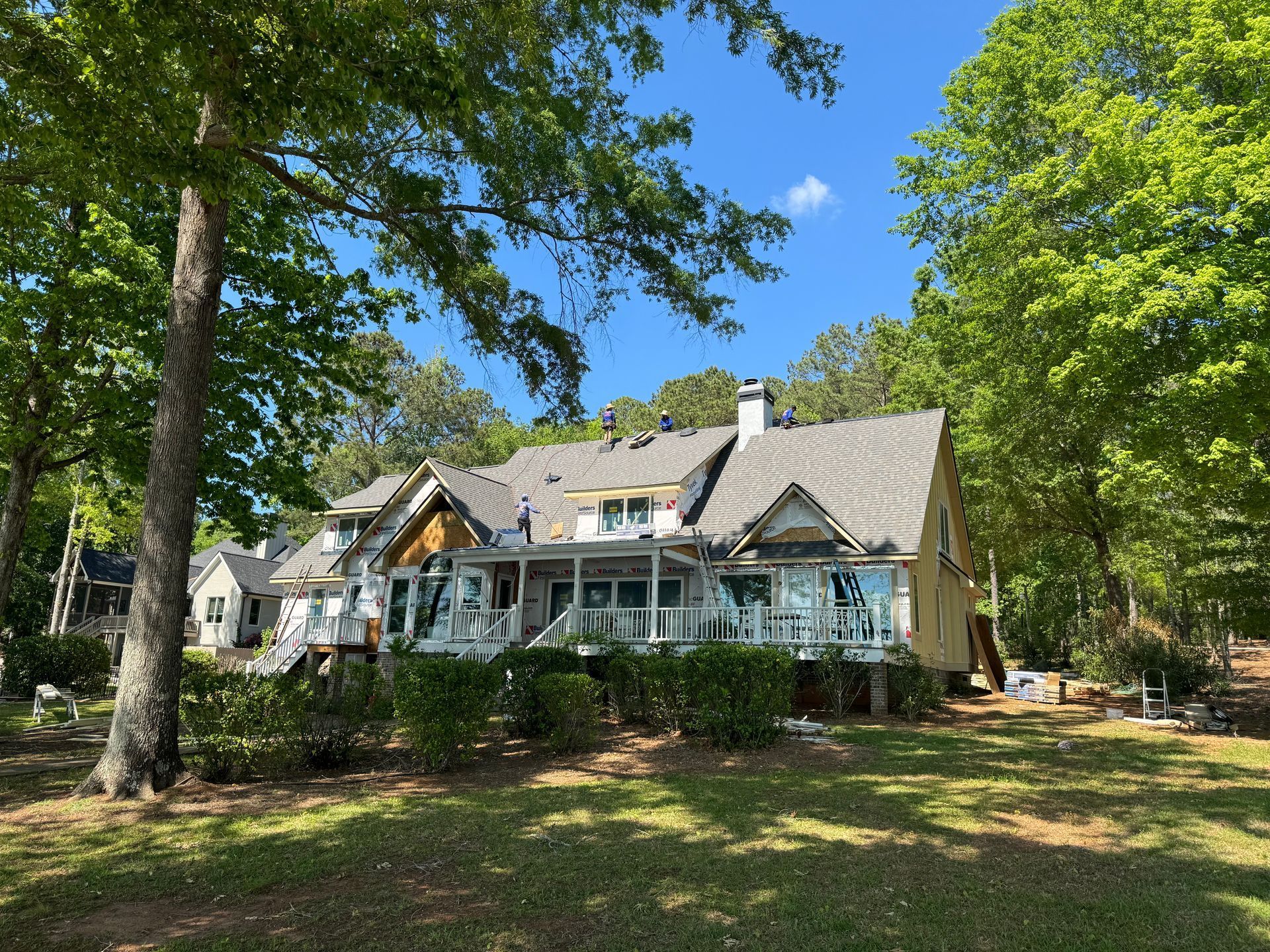 A large house is surrounded by trees and grass on a sunny day.