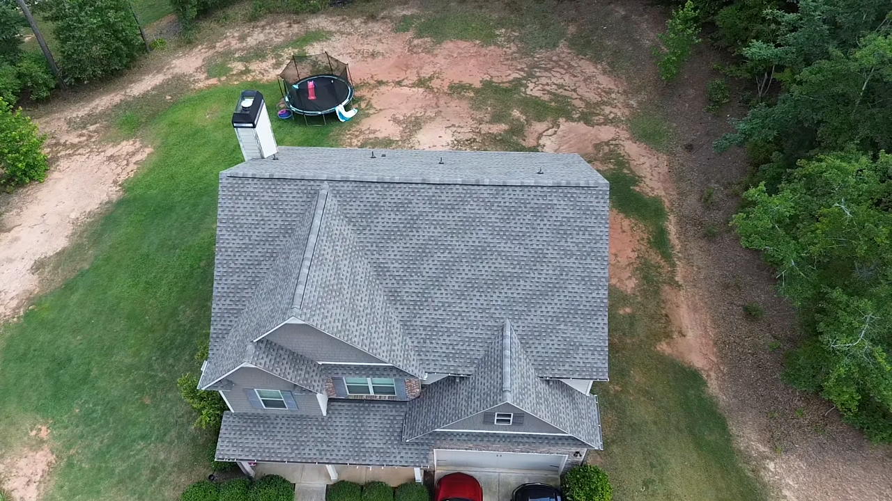 An aerial view of a house with a trampoline in the backyard.