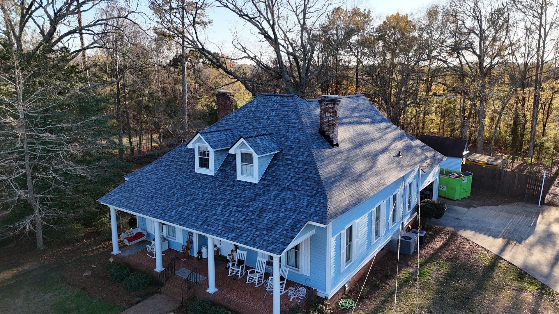 An aerial view of a blue house with a new roof.