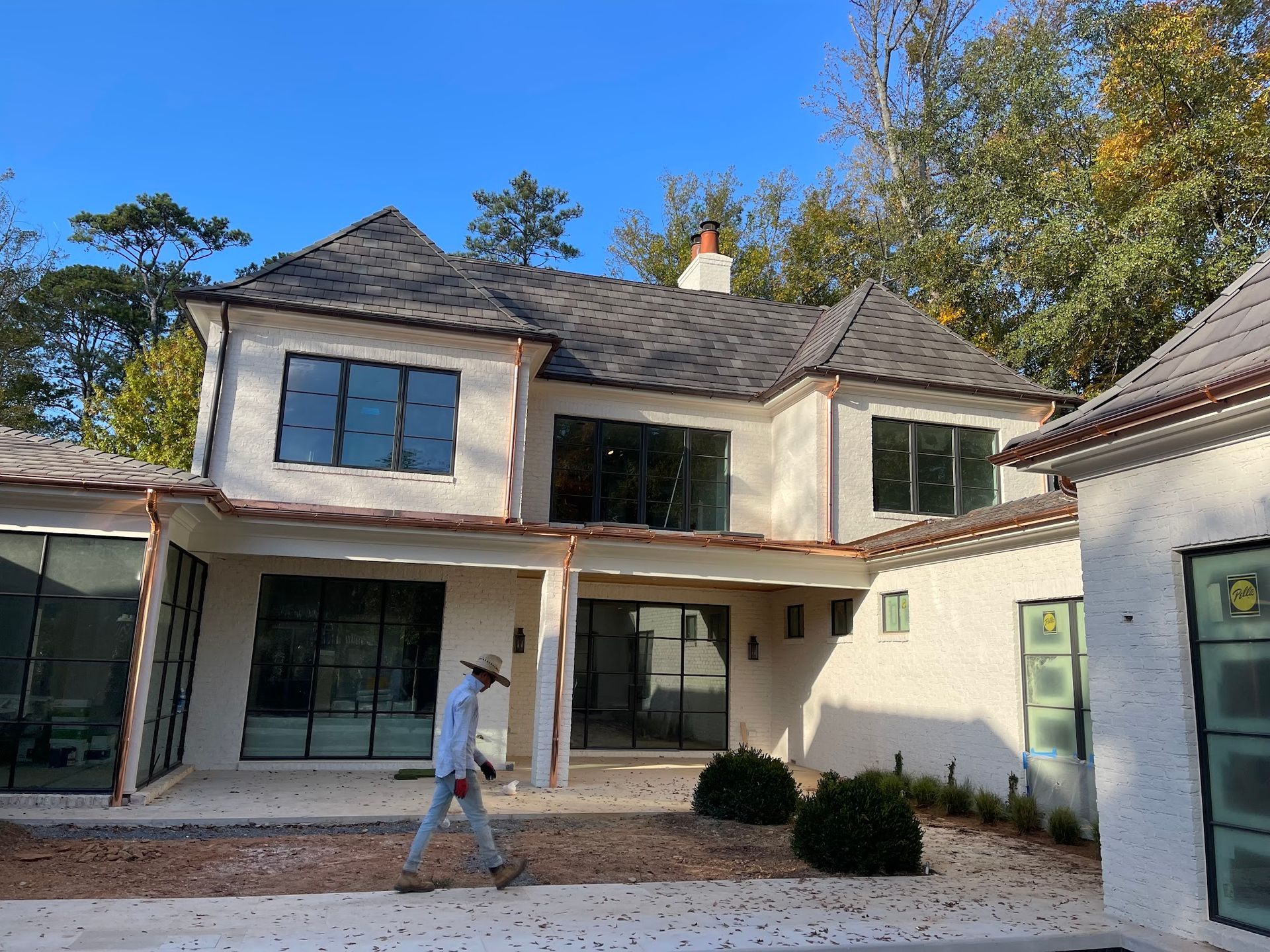 A man is walking in front of a large white house.