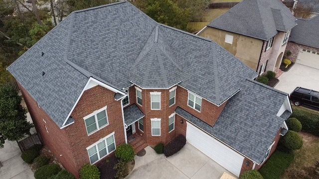 An aerial view of a large brick house with a gray roof.