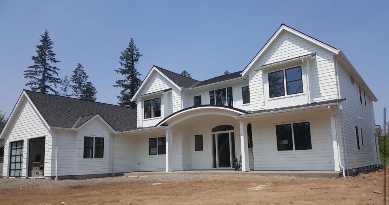 A large white house with a black roof is under construction
