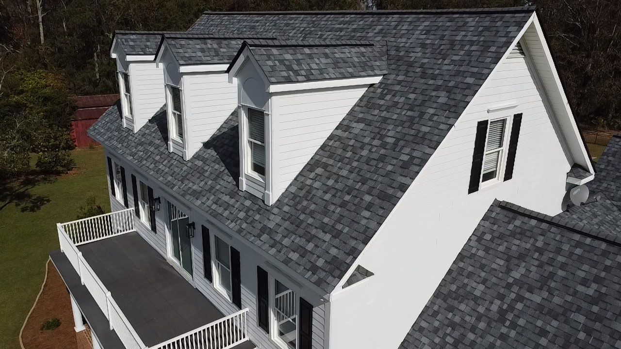 An aerial view of a large white house with a gray roof.