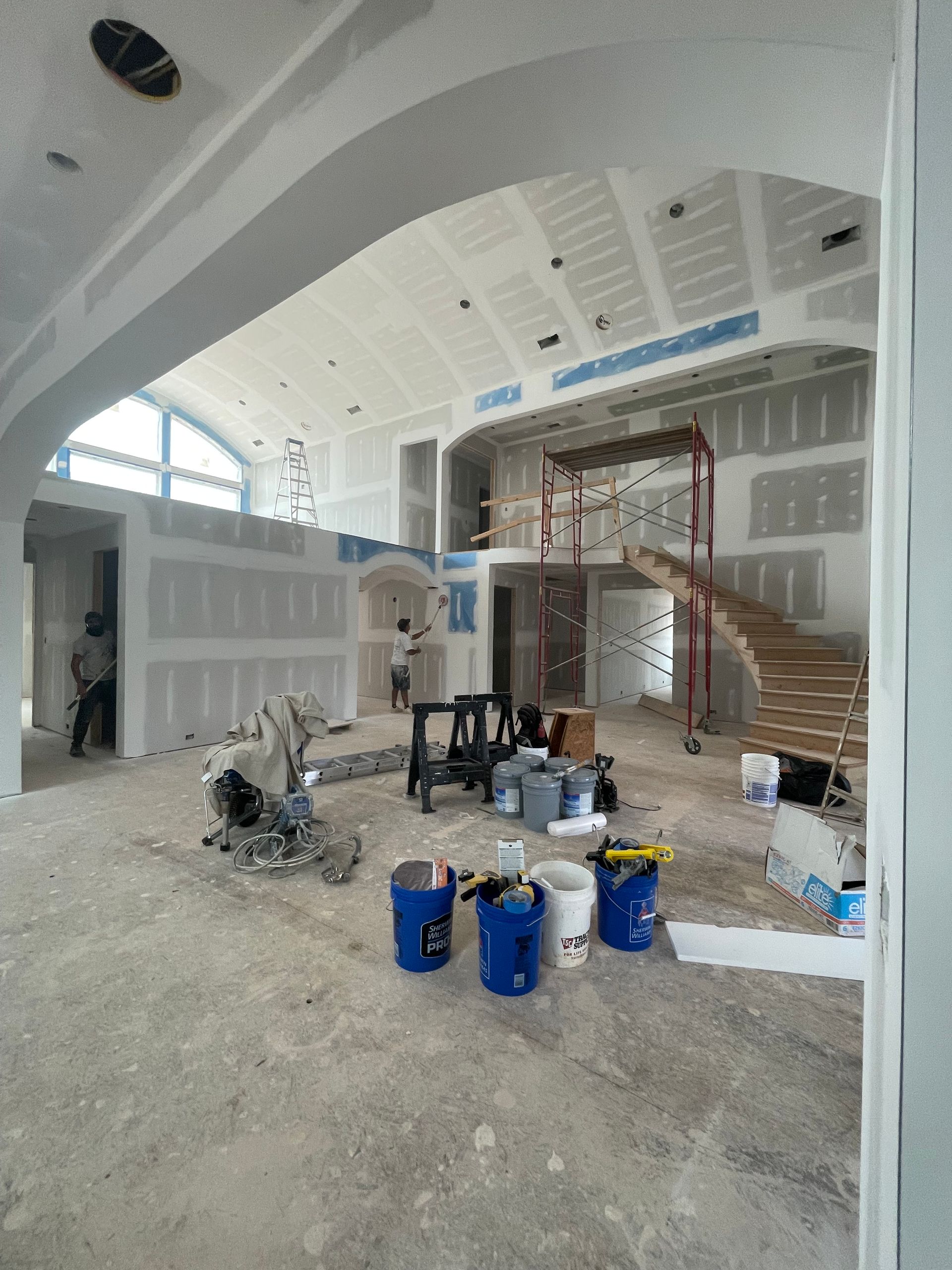 A large room with buckets of paint on the floor