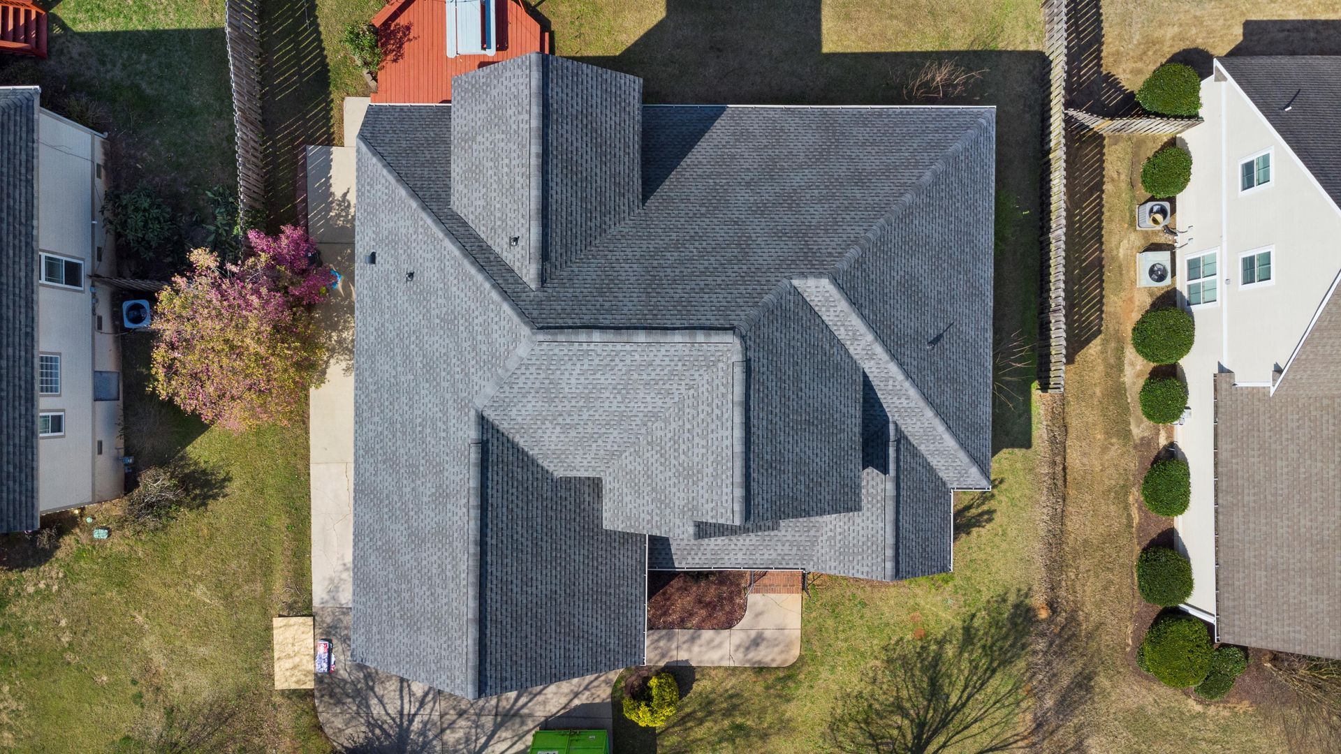 An aerial view of a house with a gray roof in a residential area.