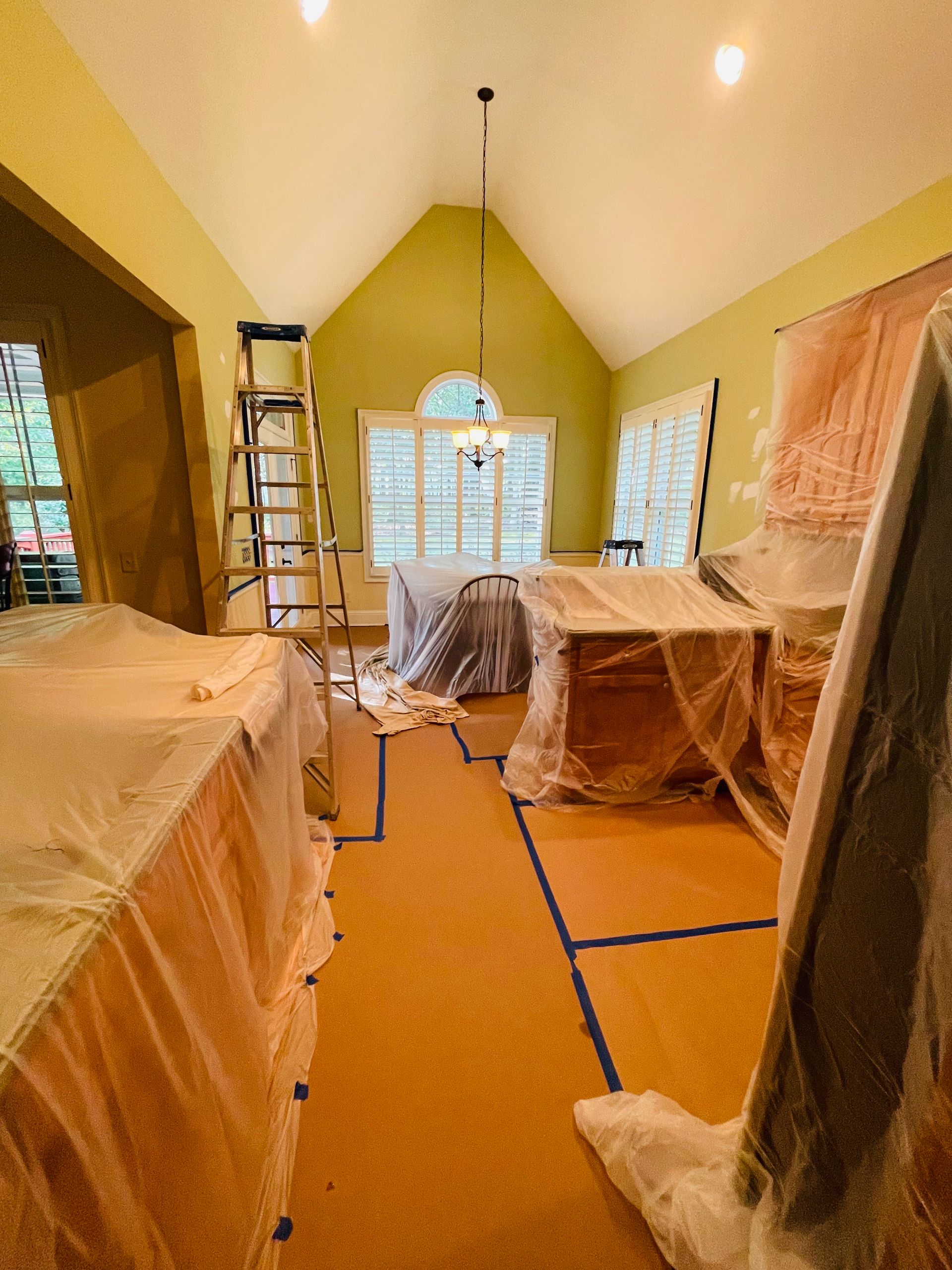 A room that is being painted with a ladder in the background.