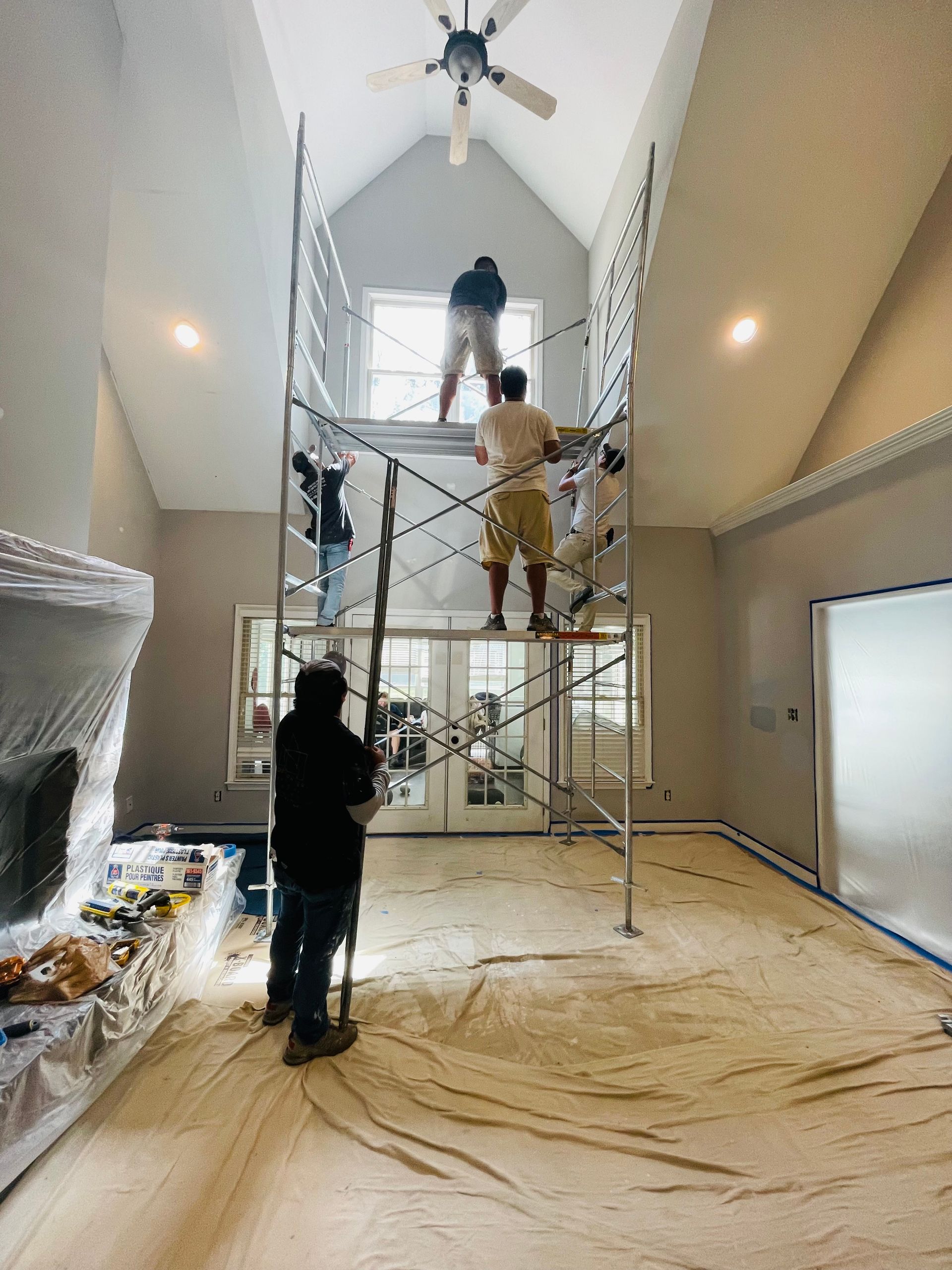 A group of people are painting a room with scaffolding.