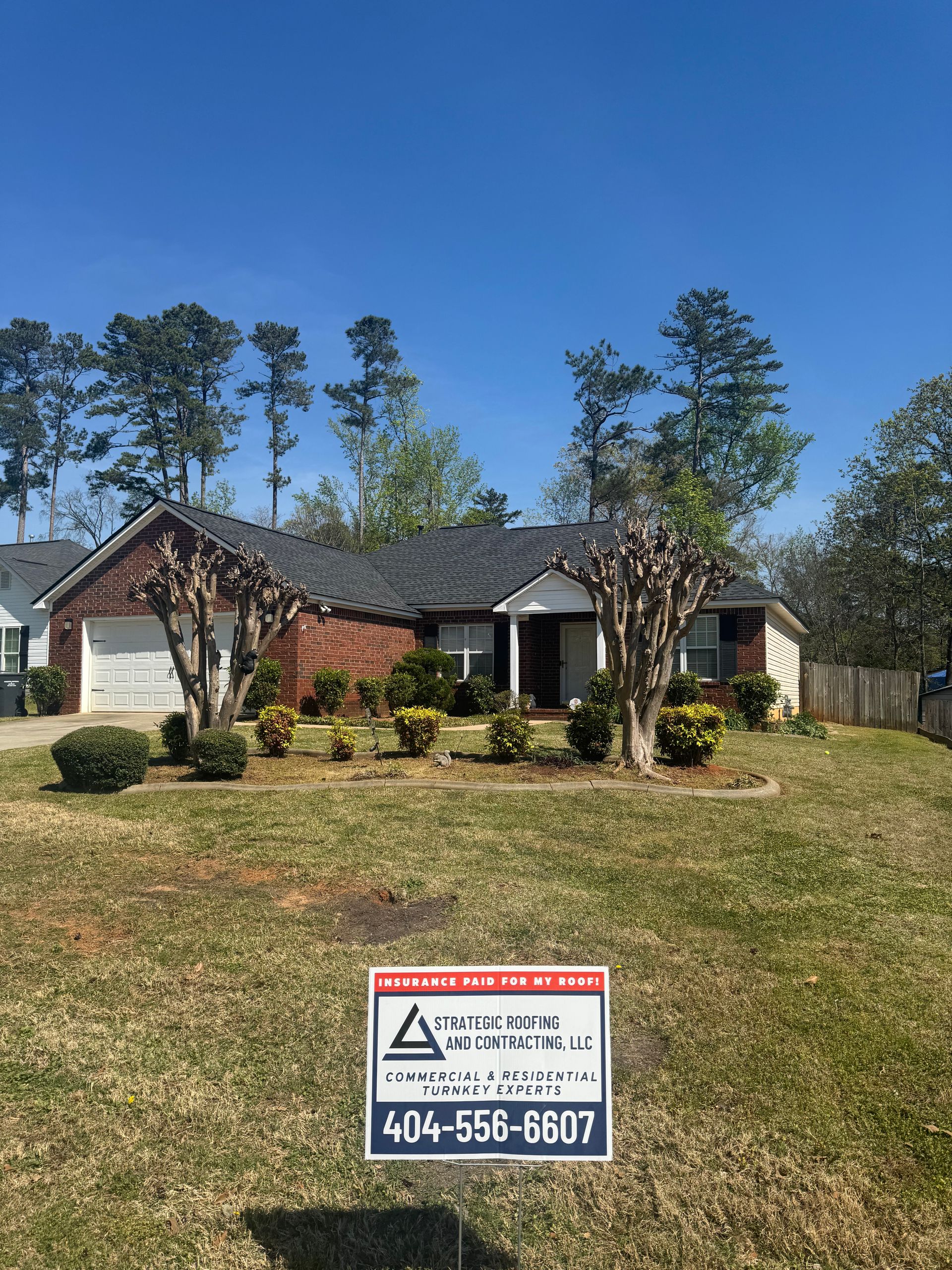 A house with a roof that has been installed and a sign in front of it.