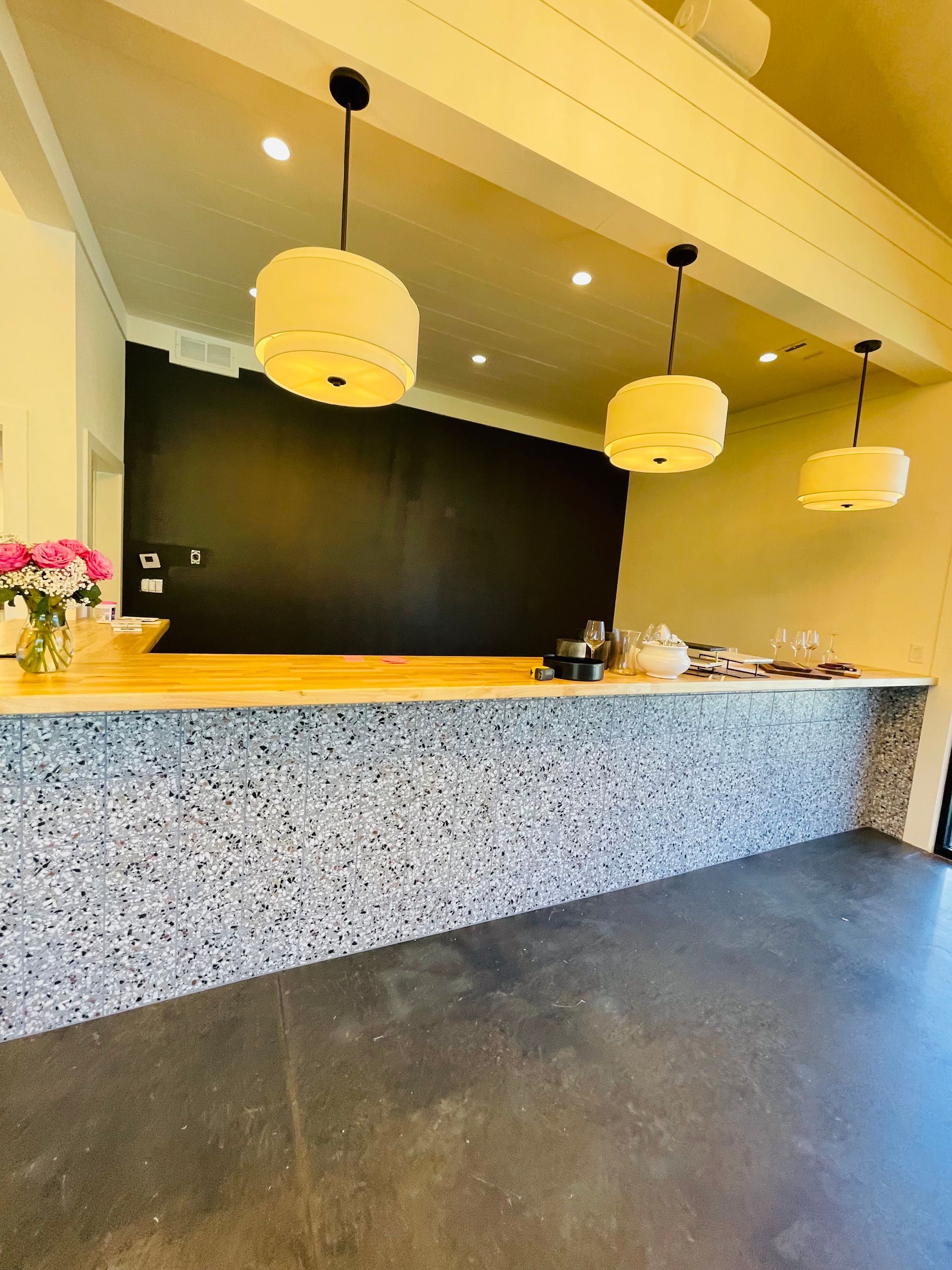 A long counter in a room with three lamps hanging from the ceiling.