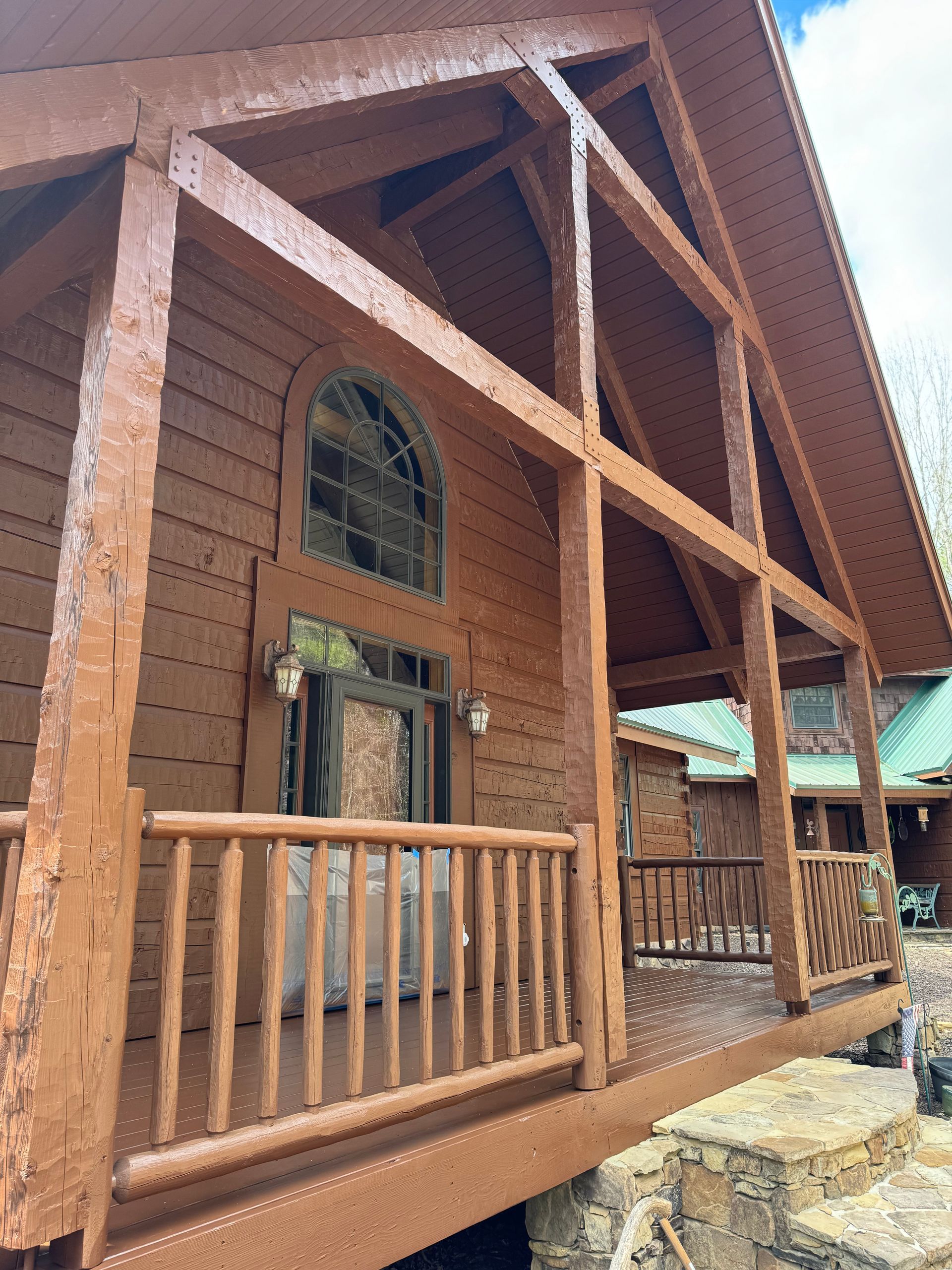 A large log cabin with a large porch and stairs