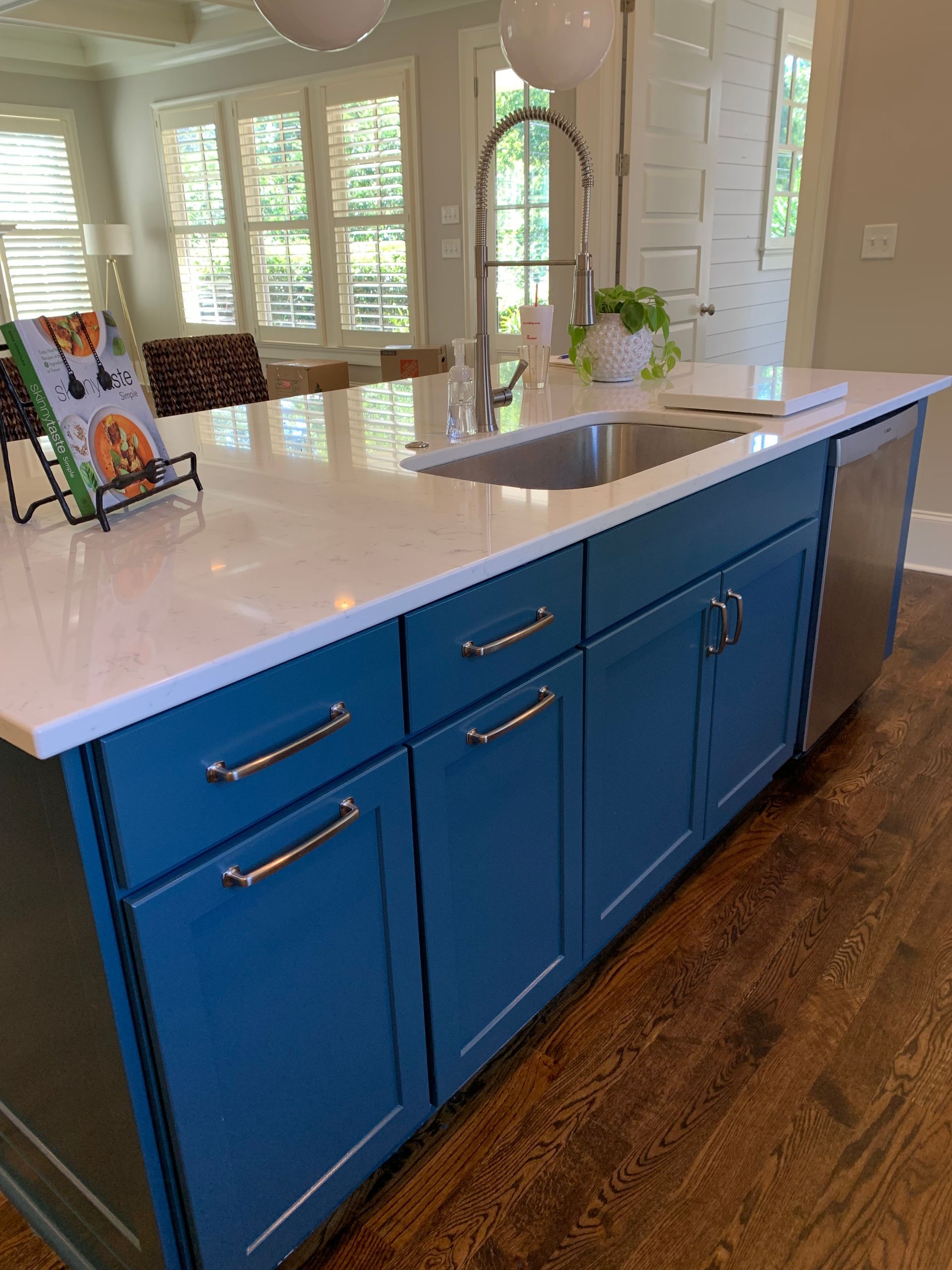 A kitchen with blue cabinets , a sink , and a book on the counter.