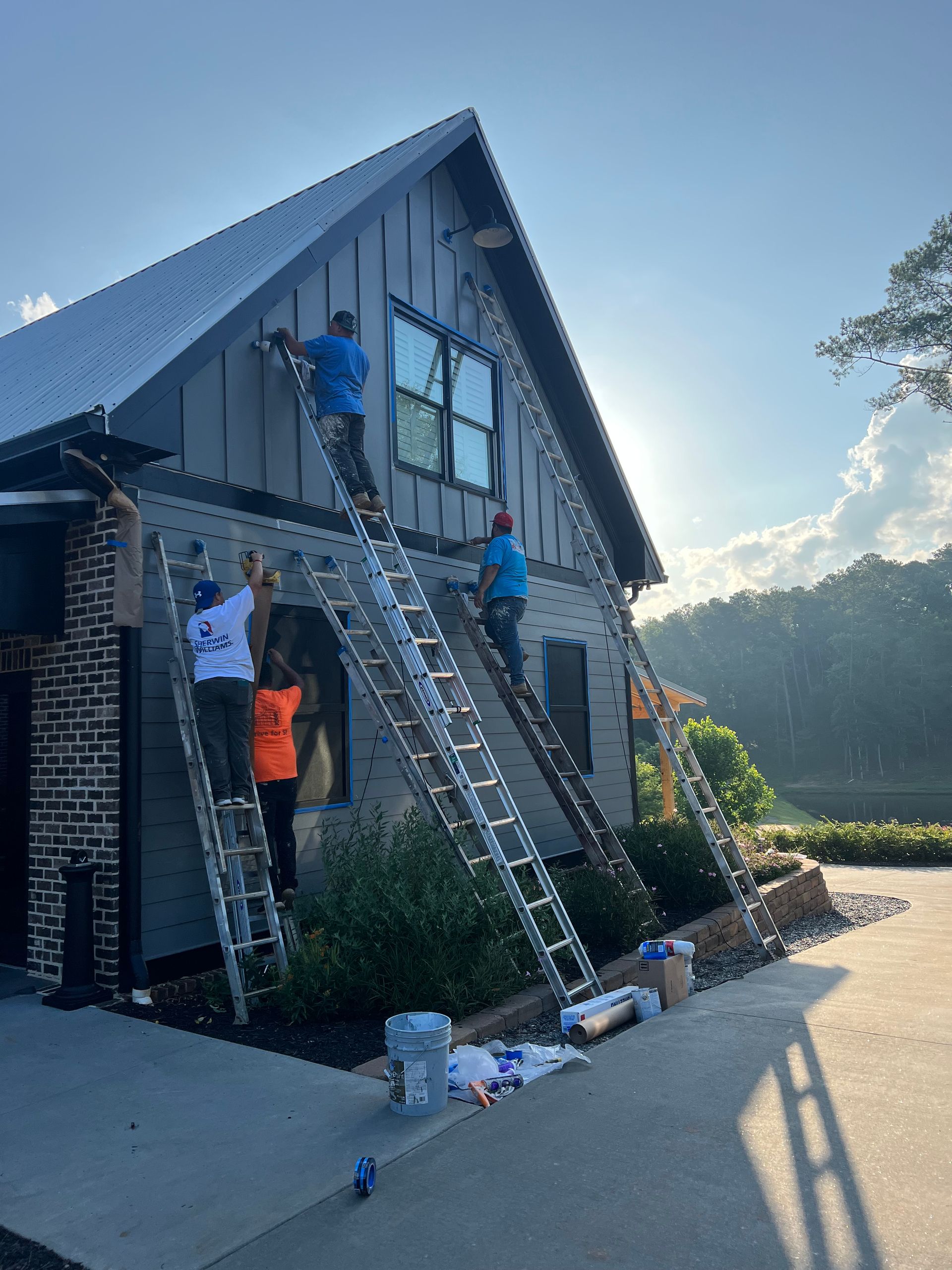 A group of people are painting a house with ladders.