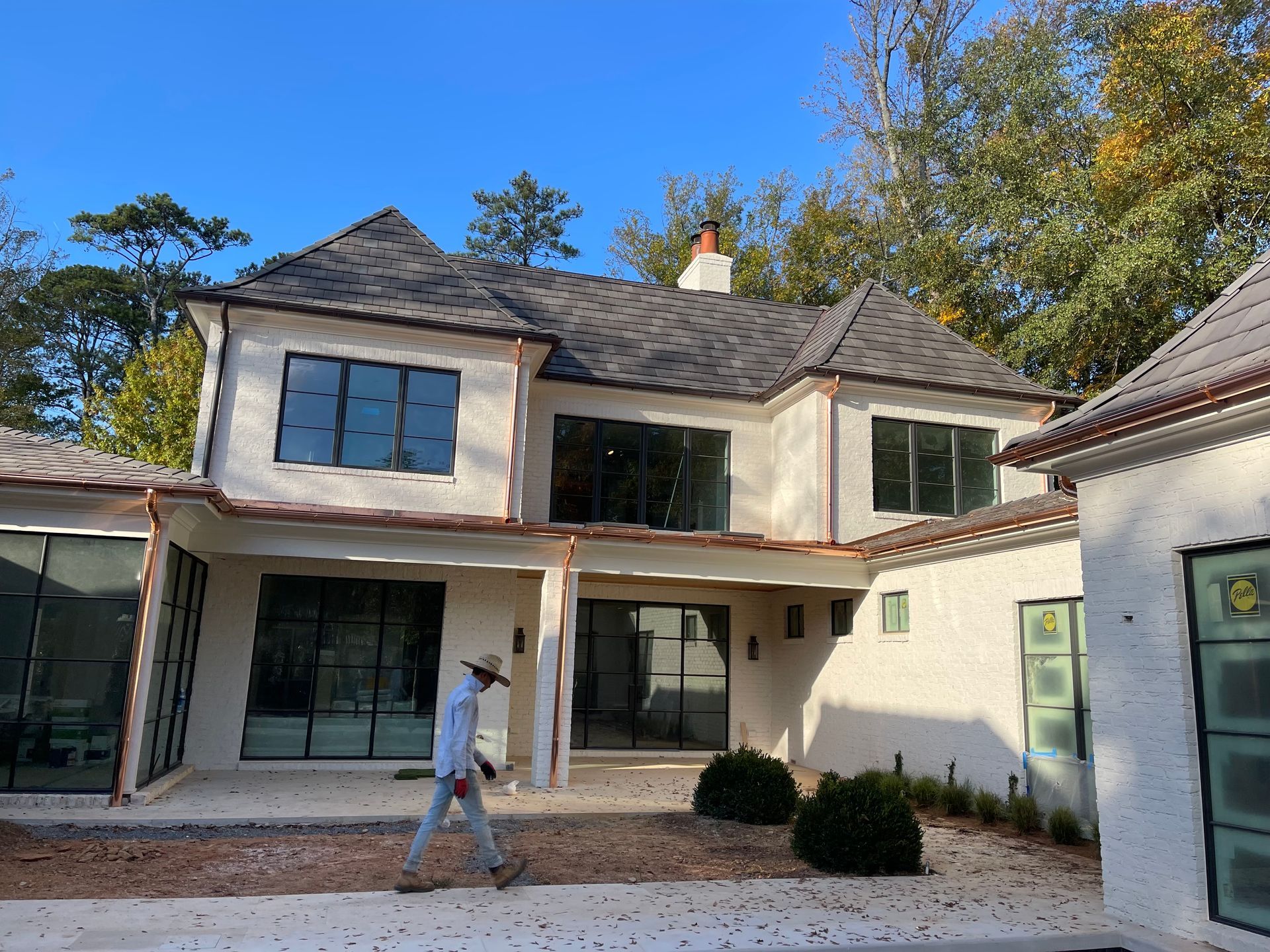 A man is walking in front of a large white house.