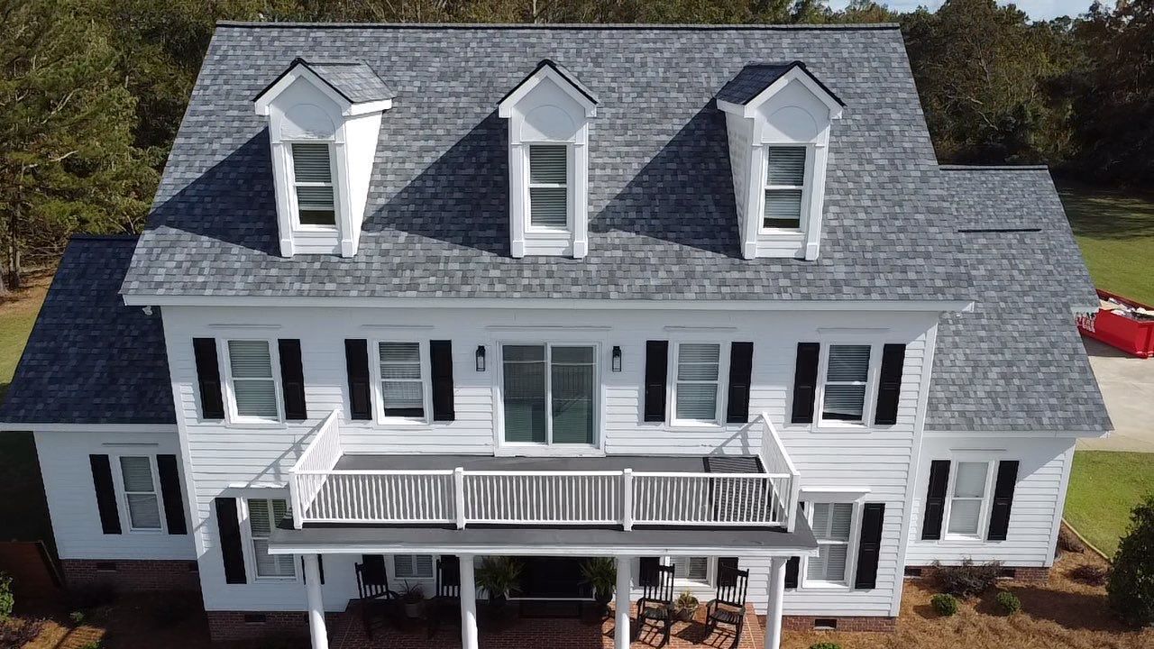 An aerial view of a large white house with a gray roof.