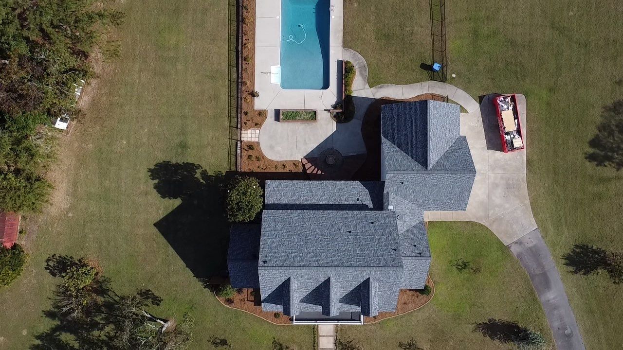 An aerial view of a house with a pool and a car parked in front of it.